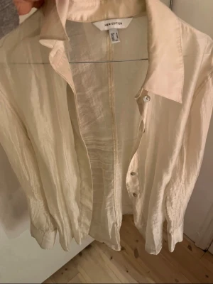 Skir skjorta från H&M Edition- knappt använd!  - Skir skjorta från H&M Edition med klassisk krage och knäppning framtill. Skjortan har långa ärmar och är tillverkad i ett lätt, glansigt material som ger en stilren look. Perfekt att styla lager på lager eller bära som den är. Knappt använd, som ny! 