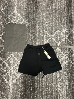 Essentials svarta shorts - Fear Of God essentials svarta shorts i S, använda 1 gång och kommer med essentials påsen. Skit sköna o perfekta för sommaren