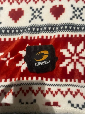Svarta handledslindor från GASP - Ett par svarta handledslindor från GASP med gula och vita logotyper. Lindorna har kardborreband och ögla för tummen, perfekta för styrketräning och gym. Materialet är elastiskt och slitstarkt för extra stöd vid tunga lyft.