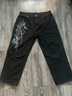 Svarta Ed Hardy jeans med tryck - Riktig feta jeans från ed Hardy säljes. Säljer då jag personligen tycker dom är aningen för stora. Kan tänka mig att byta med annat par ed Hardy(helt nya använda 3 gånger)