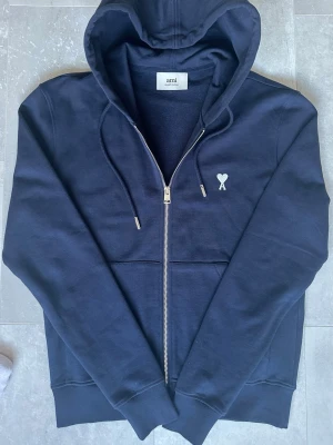 Ami zip hoodie - Snygg mörkblå hoodie från Ami med dragkedja.  Perfekta hoodien till våren. Hoodien är tillverkad i mjuk bomull och är riktigt skönt. 