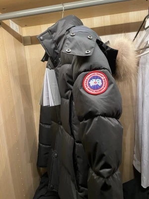 Svart dunjacka från Canada Goose - Säljer en svart dunjacka från Canada Goose med klassisk patch på ärmen och avtagbar huva med äkta päls. Jackan har dragkedja, tryckknappar och flera fickor. Perfekt för kalla vinterdagar och riktigt varm. Den är liten i storlek mer som S 