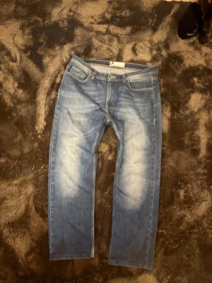 Blå  jeans från dressman - Ett par klassiska blå jeans med raka ben och snygga tvättade detaljer framtill och baktill. Jeansen har fem fickor och normal midja. Perfekta för en avslappnad och stilren look.