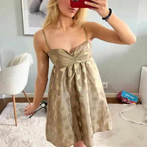 Cocktail klänning  - Supersöt kortklänning i beige med glansiga guldprickar och tunna axelband. Klänningen har en söt bystdetalj och lätt utställd kjol. Så himla fin och perfekt till fest/sommaren. Storlek 34 från Gina 💕