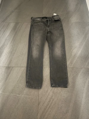 Grå raka jeans från Reaplay  för 12 eller 13 åringar  - Säljer ett par grå jeans från Reaplay med rak passform och klassisk femficksdesign som inte används på ett tag. Jeansen har snygga slitningar framtill och är tillverkade i ett mjukt denimtyg. Perfekta för en avslappnad och trendig look. Storlek 12y-13y för barn. Inga skador eller tecken på användning. Priset kan diskuteras.