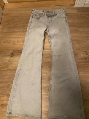 Gråa lågmidjade bootcut jeans - Snygga grå jeans med utsvängda ben och klassisk femficksmodell. Jeansen har låg midja och är i storlek 34! Säljer för de tyvärr blivit för korta för mig så väldigt lite använda💗