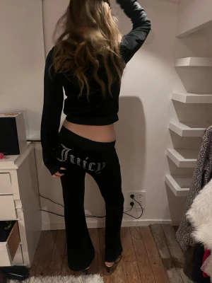 Svart Juicy Couture set  XS byxa & S tröja  - Svarta velourbyxor från Juicy Couture i storlek XS. Byxorna har bred midja med snörning, stora fickor fram och klassisk Juicy-text med paljetter på baksidan. De är uppsydda vilket gör de på gränsen till för korta för mig som är ca 167 men det borde gå enkelt att sprätta. Svart juicy tröja i S, såå mjuk och snygg!! Säljer hela settet för 1000 och en för 600. 