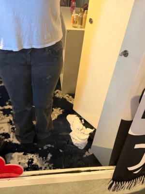 Mörkgrå raka jeans - Säljer ett par mörkgrå jeans med raka ben och klassisk femficksdesign. Jeansen har knapp- och dragkedjegylf samt detaljerade bakfickor med knapp. Perfekta för en avslappnad och stilren look.