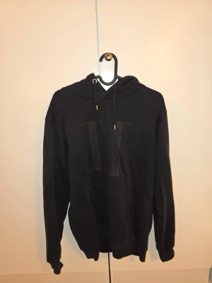 Svart hoodie från Les Deux - Les Deux hoodie – (S) Hoodie från Les Deux. Storlek: S Skick: Acceptabelt skick. Anmärkning: Ett öljet (metallringen vid snöret) saknas på ena sidan.