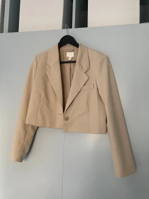 Kavaj - Kavaj/blazer i fint skick. Beige kroppad modell med axelvaddar. Strl M men passar även S!