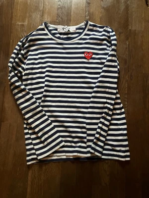 *äkta* CDG Play blå vit randig långärmad tröja - Säljer min äkta cdg play då den är förliten. Storlek är M men skulle säga att den sitter som  en S då det är japansk passform