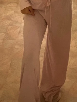 Ljusrosa mjuka loungewear-byxor - Supermysiga ljusrosa loungewear-byxor med vida ben och dragsko i midjan. Perfekta för chill hemma och riktigt sköna mot huden. Materialet ser ut att vara mjukt och stretchigt, vilket ger en avslappnad och bekväm känsla.