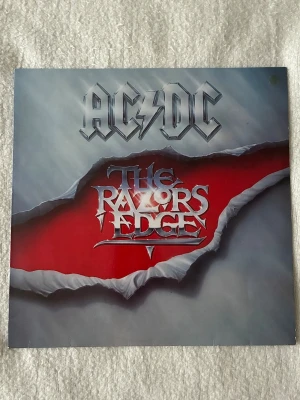AC/DC The Razors Edge vinyl/ LP - Säljer ett begagnat vinylalbum med AC/DC:s klassiska skiva The Razors Edge (Vinyl LP).  Skivan är i mycket fint skick utan synliga repor. Vinylen är köpt på en musikaffär i sthlm och borde därför även fungera att spelas, jag själv har inte testat.  Omslaget har några mindre skavanker (se bilder), men inget som påverkar helhetsintrycket.  Hör av dig vid frågor! Annars är det bara att trycka på ”köp nu” för att få hem det ikoniska albumet till din samling!💯🔥 