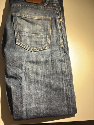 Blå hiut denim co jeans tvättade - Snygga slitningar med coola detaljer, blå jeans. Har en del slitningar under men går enkelt att fixa genom att sy ihop.