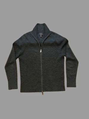 Mörkgrå ziptröja från H&M - Mörkgrå stickad ziptröja från H&M med hög krage och hel dragkedja framtill. Tröjan har lång ärm och är tillverkad i ett mjukt, tunt material som passar perfekt till lager-på-lager-stil.