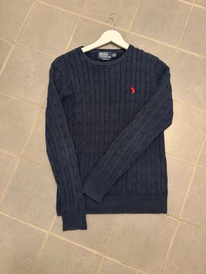 Polo Ralph Lauren tröja - Mörkblå kabelstickad tröja från Polo Ralph Lauren med klassisk passform. Bra skick fråga om bilder eller funderingar 