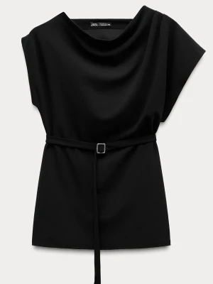 Svart topp med bälte från Zara - Stilren svart topp från Zara med lös passform och ett smalt bälte i midjan. Toppen har korta ärmar och en mjukt draperad halsringning som ger en elegant look. Perfekt att styla med både jeans och kjol.