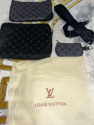 Louis Vuitton Monogram handväska set - Säljer ett set med Louis Vuitton handväska i svart och grått med klassiskt monogrammönster. Setet inkluderar en större väska, två mindre accessoarer och en justerbar axelrem. Materialet är canvas med detaljer i läder. Dustbag medföljer.