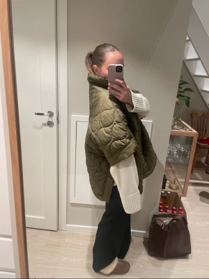 Olivgrön quiltad dunväst - Säljer en olivgrön quiltad dunväst med hög krage och boxig passform. Västen har ett coolt rutmönster och är perfekt att slänga över en stickad tröja. Oversized look och riktigt trendig färg för säsongen.