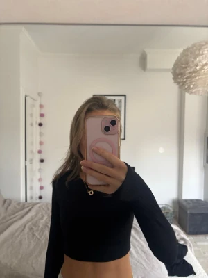 Svart cropped träningströja Aim'n - Snygg svart långärmad cropped träningströja från Aim'n. Tillverkad i ett stretchigt funktionsmaterial som andas, perfekt för gymmet eller löpning. Tröjan har rund halsringning och diskreta ribbade detaljer för extra stil.