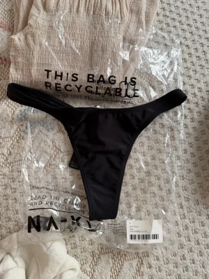 Svart bikiniunderdel i string från NA-KD - Helt ny, i original förpackningen som på bilden. 