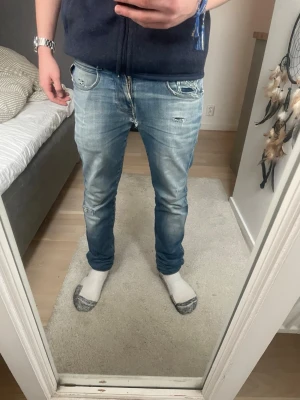 Slim fit ljusblå slitna jeans - Säljer ett par slim fit ljusblå jeans med slitningar och detaljerade revor på knä och fickor. Jeansen har 2 hål vid pungen och ett hål på baksidan annars ör jeans rikigt schyssta 