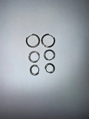 Sats med silverfärgade ringörhängen - Säljer ett set med sex stilrena ringörhängen i olika storlekar. Alla är i silverfärg och har en enkel, klassisk design utan dekorationer. Perfekta för att mixa och matcha flera hål i öronen. 