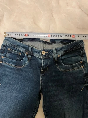 Ltb jeans valerie - Snygga blå jeans från LTB med klassisk femficksdesign och raka ben. Jeansen har låg midja, silverfärgade nitar och knapp samt diskreta slitningar för en trendig look. Perfekta för dig som gillar en tidlös och avslappnad stil.