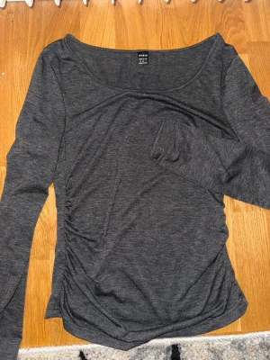 Mörkgrå långärmad topp  - Mörkgrå långärmad topp från Shein med rund halsringning och figurnära passform. Tillverkad i mjukt syntetmaterial som känns bekvämt mot huden. Perfekt att styla med jeans eller kjol för en enkel och snygg look.