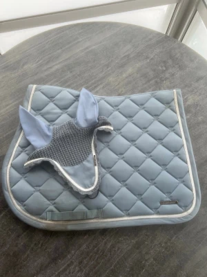 Ljusblått lamicell sett - Jätte fint sett från lamicell Används 1 gång på tävling så endast lite smutsigt vid sadelgjorden (går säkert att få bort) Både schabraket och huvan är i storlek full