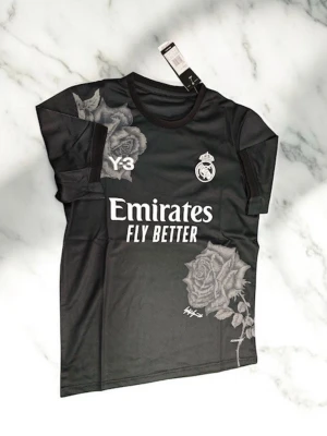 Svart Real Madrid fotbolls T-Shirt - Svart Real Madrid T-Shirt med rosor som design. Storlek S. Helt ny Oanvänd.