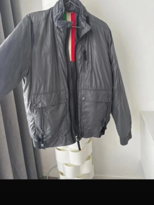 Mörkgrå vindjacka från Patrizia Peppe - Snygg mörkgrå vindjacka från Patrizia peppe med hög krage och dragkedja framtill. Jackan har en liten spricka bakifrån 