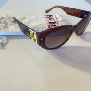 Bruna cat eye solglasögon från Guess - Säljer dessa fina solglasögon från guess med följande dustbag, kommer ej till användning längre. Det finns också en liten repa som syns i tredje bilden men den påverkar inte synen eller hur solglasögonen ser ut! Solglasögonen har även UV-skydd   Köpta från Zalando för ca 700kr   Testa gärna på glasögonen virtuellt: https://www.misterspex.se/p/sg/6844931?srsltid=AfmBOoqxqwEQrEq2je2cm95ImtD4CpO7Turz7qYNJVG7j51Os-qZjTGe 