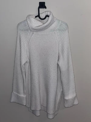 Vit polotröja i ribbstickat - Mysig vit ribbstickad polotröja med bred krage och långa ärmar. Tröjan har uppvikta muddar och en avslappnad passform som ger en chill vibe. Perfekt för lager på lager under kalla dagar.