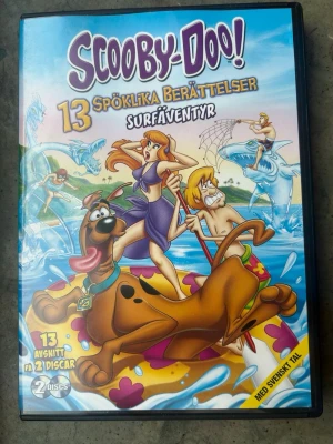 Scooby doo: 13 spöklika berättelser surfäventyr dvd - Scooby doo 13 spöklika berättelser surfäventyr dvd. Speltiden är 273 minuter.  Finns på språk: Svenska, Engelska, Franska, Spanska   OBS! Innehåller enbart 1 skiva, disc 2 saknas  OBS!! skivorna är begagnade så det kan förekomma repor/hairlines på skivorna, men då jag kollar igenom alla filmer jag säljer garanterar jag att alla funkar felfritt om inget annat står! :)