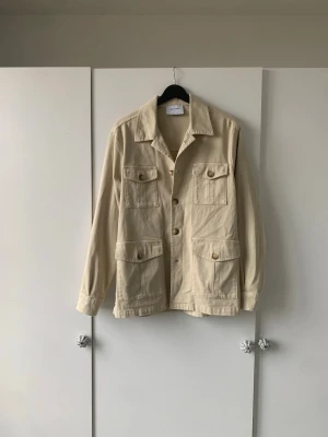 Beige overshirt Gran Sasso - Stilren beige overshirt från Gran Sasso i bomull med fyra stora fickor framtill och knappar hela vägen. Rak passform och klassisk krage ger en avslappnad look. Perfekt att slänga över en t-shirt för en enkel men snygg outfit. Nypris 4500kr storlek 46