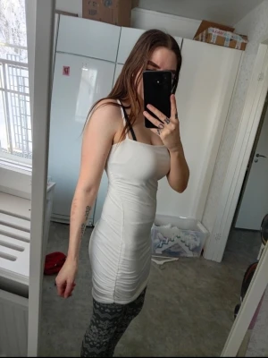 Vit tight kortklänning med smala axelband - Säljer en vit, tight och kort klänning med smala axelband. Klänningen har en enkel och stilren design som framhäver figuren. Perfekt för dig som gillar minimalistisk stil och vill ha något som känns både trendigt och bekvämt.