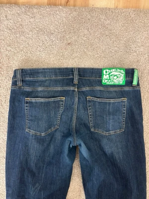 Blå bootcut jeans från Cheap Monday - Säljer ett par klassiska blå bootcut jeans från Cheap Monday. Jeansen har en lätt tvättad look och är tillverkade i denim med raka ben som slutar i en lätt utsvängd passform. De är lite nötta i grenen men tror det beror på att tyget är ganska tunt och stretchigt så det har slitits lite även fast jag använt fåtal gånger. Storlek 32/36