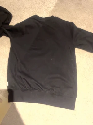 Svart sweatshirt från Lindbergh - En svart sweatshirt från Lindbergh i relaxed fit. Tröjan har rund halsringning och långa ärmar. Enkel och stilren design utan tryck eller mönster, perfekt för en avslappnad look.