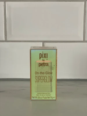 Pixi On-the-Glow Superglow Highlighter - Pixi by Petra On-the-Glow Superglow är en highlighter i stickformat som ger en intensiv glow. Förpackningen är ljusgrön med guldiga detaljer och innehåller 19g. Enkel att applicera direkt på huden för en fräsch, återfuktad finish.