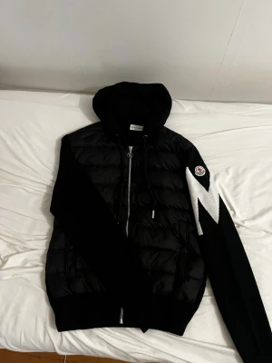 Moncler cardigan  - Säljer en svart cardigang från Moncler med huva och dragkedja. Perfekt för dig som vill ha en snygg och stilig look! Jackan kan sitta som en S storlek pris kan diskuteras 
