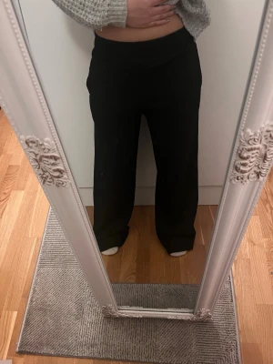 Svarta vida mjukisbyxor - Ett par svarta mjukisbyxor med hög midja och raka, vida ben. Byxorna har en enkel och clean look utan synliga loggor eller detaljer. Perfekta för en chill och avslappnad stil. Materialet ser mjukt och bekvämt ut, perfekt för att bara slappa.