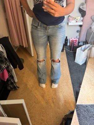 Blåa bootcut jeans med hål - Säljer ett par ljusblå bootcut jeans med slitna hål på båda knäna. Jeansen är låg midjade och knappast använda. Säljer då de inte kommer till användning. Jeansen är från Nelly. Skriv privat om du har fler frågor 🩷