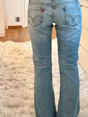 Levi's ljusblå bootcut jeans - Ljusblå bootcut jeans från Levi's med klassiska bakfickor och röd logotagg. Jeansen har en lätt tvättad look, fem fickor och normal midja. Perfekta för en avslappnad och trendig stil. Köpta på Vinted men passar Tyvvär inte på mig. Skriv för bild!!