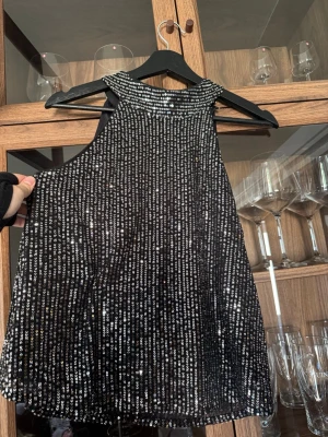 Svart paljettopp med halterneck - Säljer en svart ärmlös topp täckt med glittriga paljetter och halterneck. Jätte fin paljett topp som är perfekt till fest. Den är knytning vid halsen samt lite öppen i ryggen. Jag har använt den 2-3 gånger. Köpt på zalando för 429kr🫶🏼