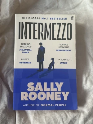 Intermezzo av Sally Rooney - Säljer romanen 'Intermezzo' av Sally Rooney. Boken har ett blåvitt omslag med en siluett av en man och en hund. Romanen handlar om två bröder, Peter och Ivan, och deras liv efter en förlust. Perfekt för dig som gillar samtida skönlitteratur.