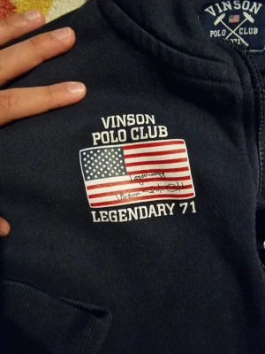 Marinblå hoodie från Vinson Polo Club - Tja! Säljer en snygg Polo club zip upp den är i bra skicka men har ett litet hål på en av händerna storlek är S