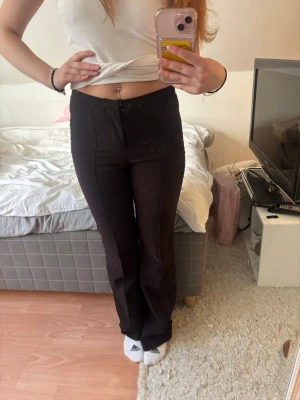 Svarta utsvängda kostymbyxor - Säljer ett par svarta kostymbyxor med utsvängda ben och hög midja. De sitter tight upptill men släpper ut vid anklarna. Perfekta till en enkel topp eller hoodie.