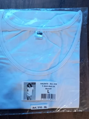 Vit t-shirt från Valente i bomull storlek L  - Klassisk vit t-shirt från Valente i mjuk bomull. Enkel och stilren design med rund halsringning och korta ärmar. Perfekt basplagg att matcha med allt i garderoben. Storlek L