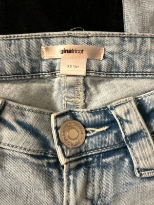 Ljusblå jeans från Gina Tricot XS - Säljer ett par ljusblå jeans från Gina Tricot i storlek XS. Jeansen har raka ben, klassisk femficksmodell och snygg broderad detalj på bakfickan. Tillverkade i denim med en cool tvättad look och knappgylf framtill.